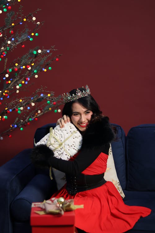 Woman in Red Dress and Crown Sitting with Christmas Gift