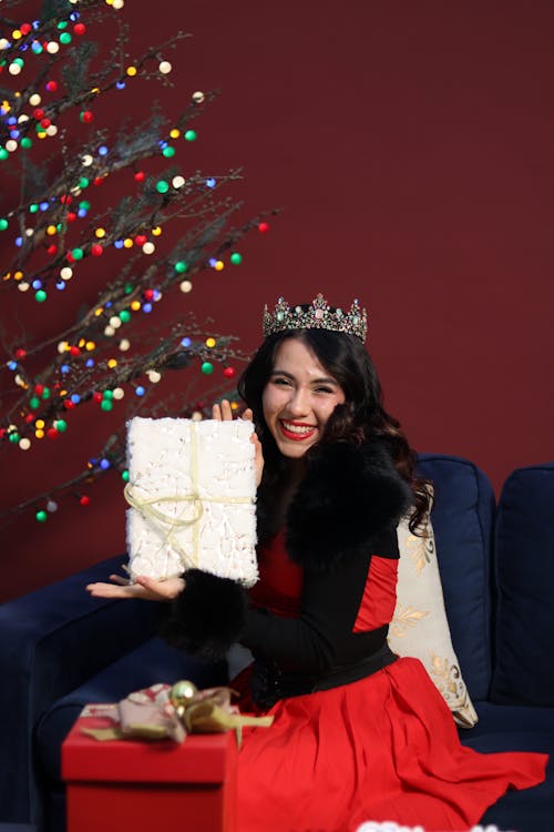 Smiling Woman in Red Dress Sitting with Christmas Gift