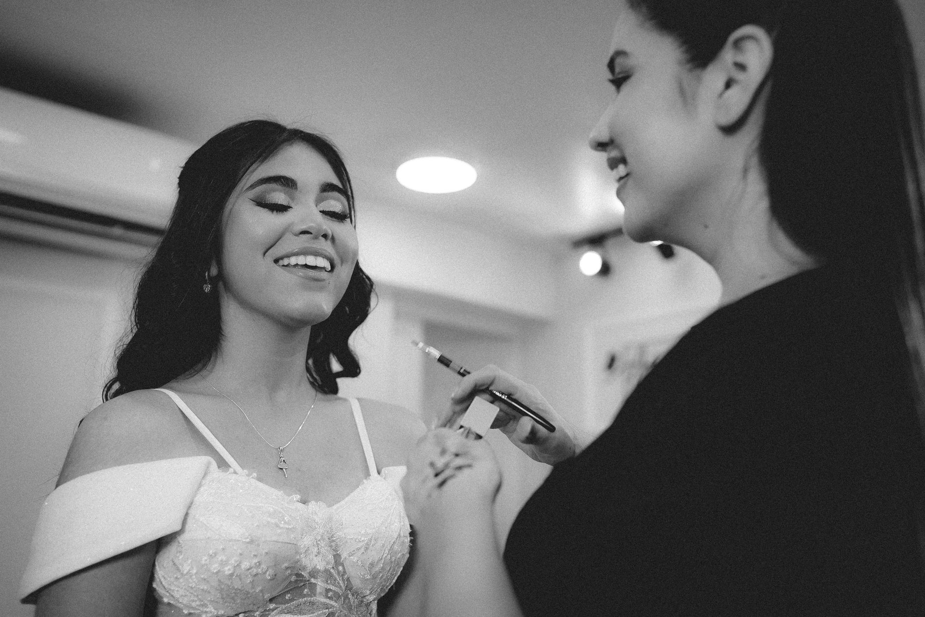 A joyful bride gets her makeup done, radiating happiness before her wedding ceremony.