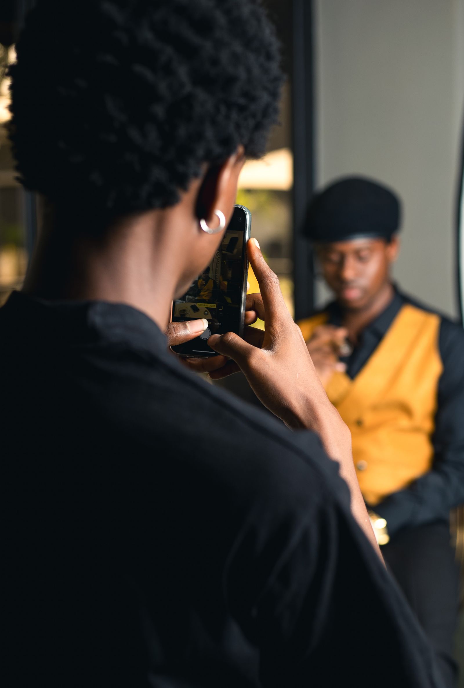 Créateur africain photographiant un modèle stylé avec son smartphone