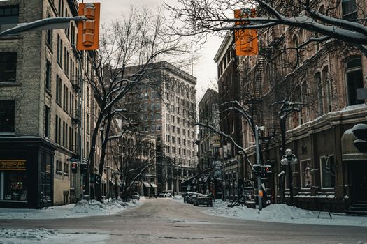 A tranquil urban scene of a snow-covered street in Winnipeg during winter, showcasing historic architecture.