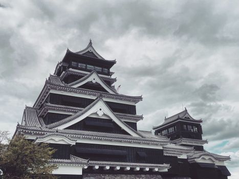 Majestic view of Kumamoto Castle under dramatic cloudy skies in Kumamoto, Japan.