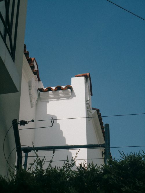 Free Low angle view of a white building with orange roof tiles against a clear blue sky. Stock Photo