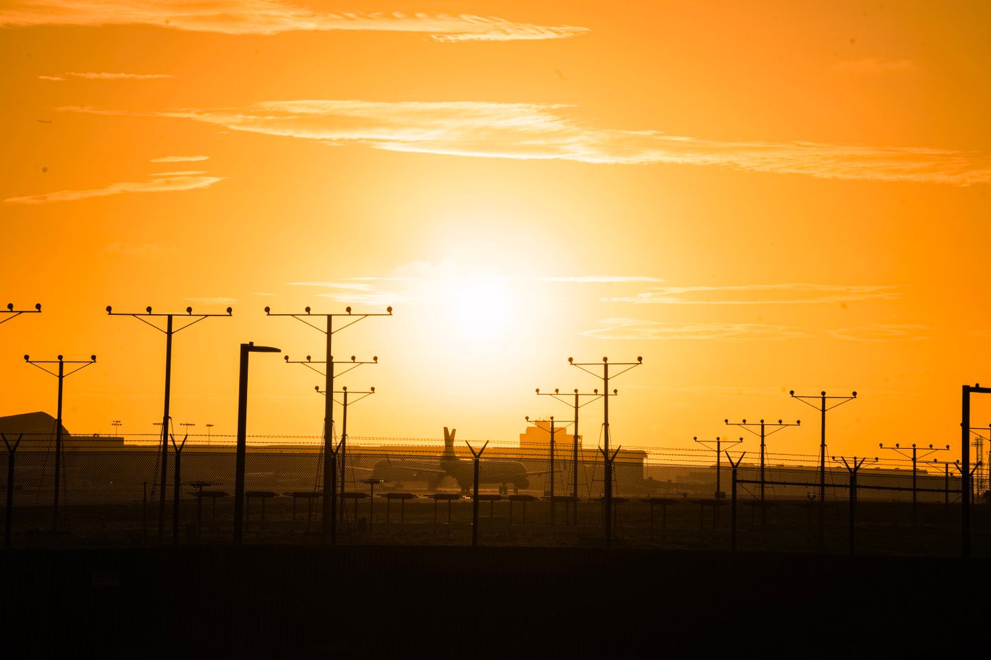 Golden sunset over LAX airport with silhouetted power lines and runway infrastructure