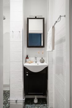 A sleek bathroom design featuring a mirror, sink, and towel set against white tiled walls.