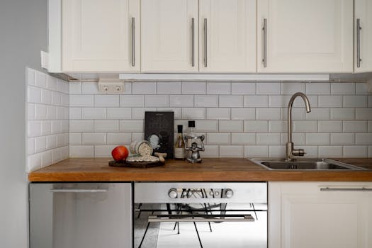 Stylish modern kitchen interior with white cabinets and wooden countertop, featuring kitchen essentials.