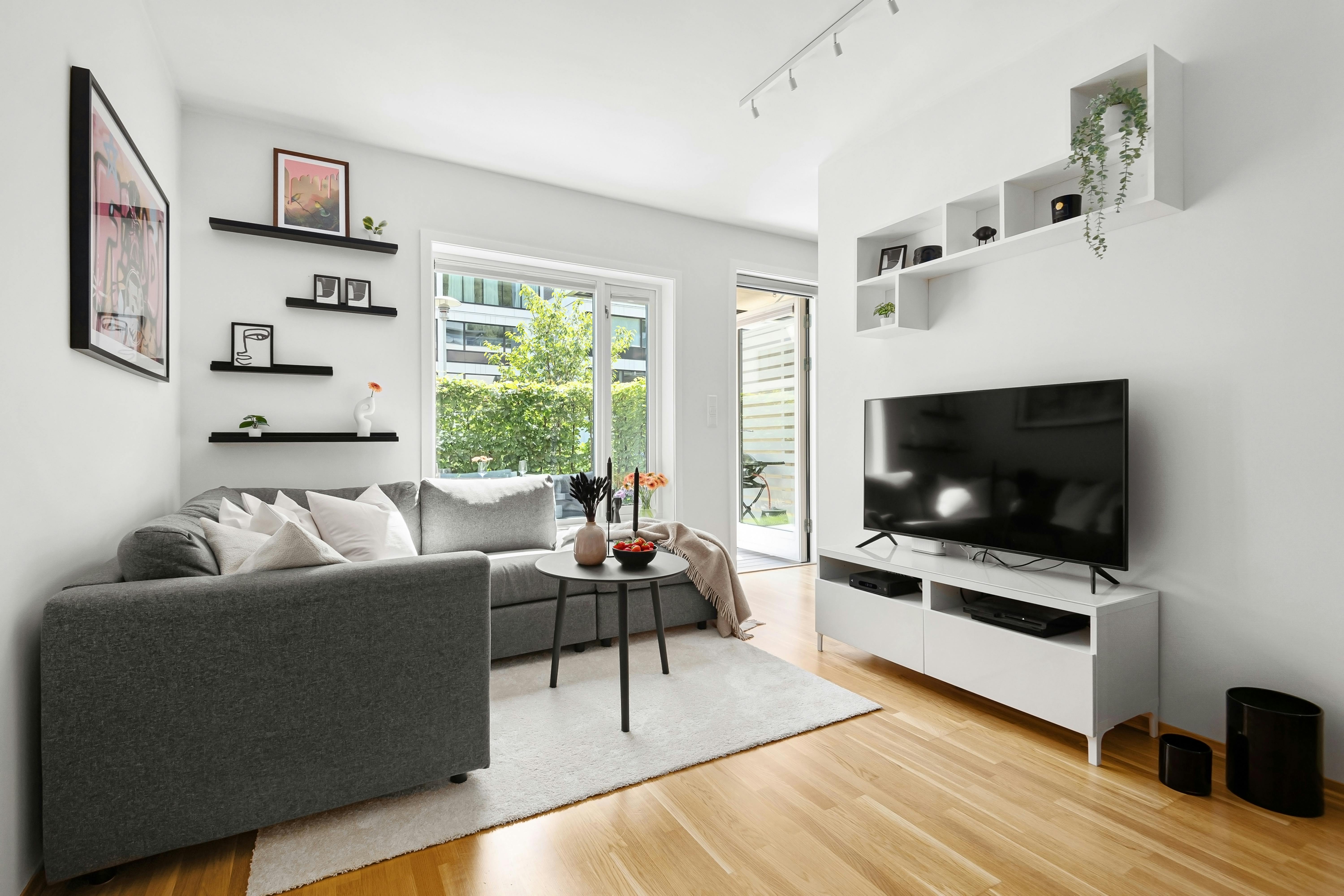 Helles kleines Wohnzimmer mit schwebendem Lowboard und wandmontiertem Fernseher in ruhigen Naturtönen