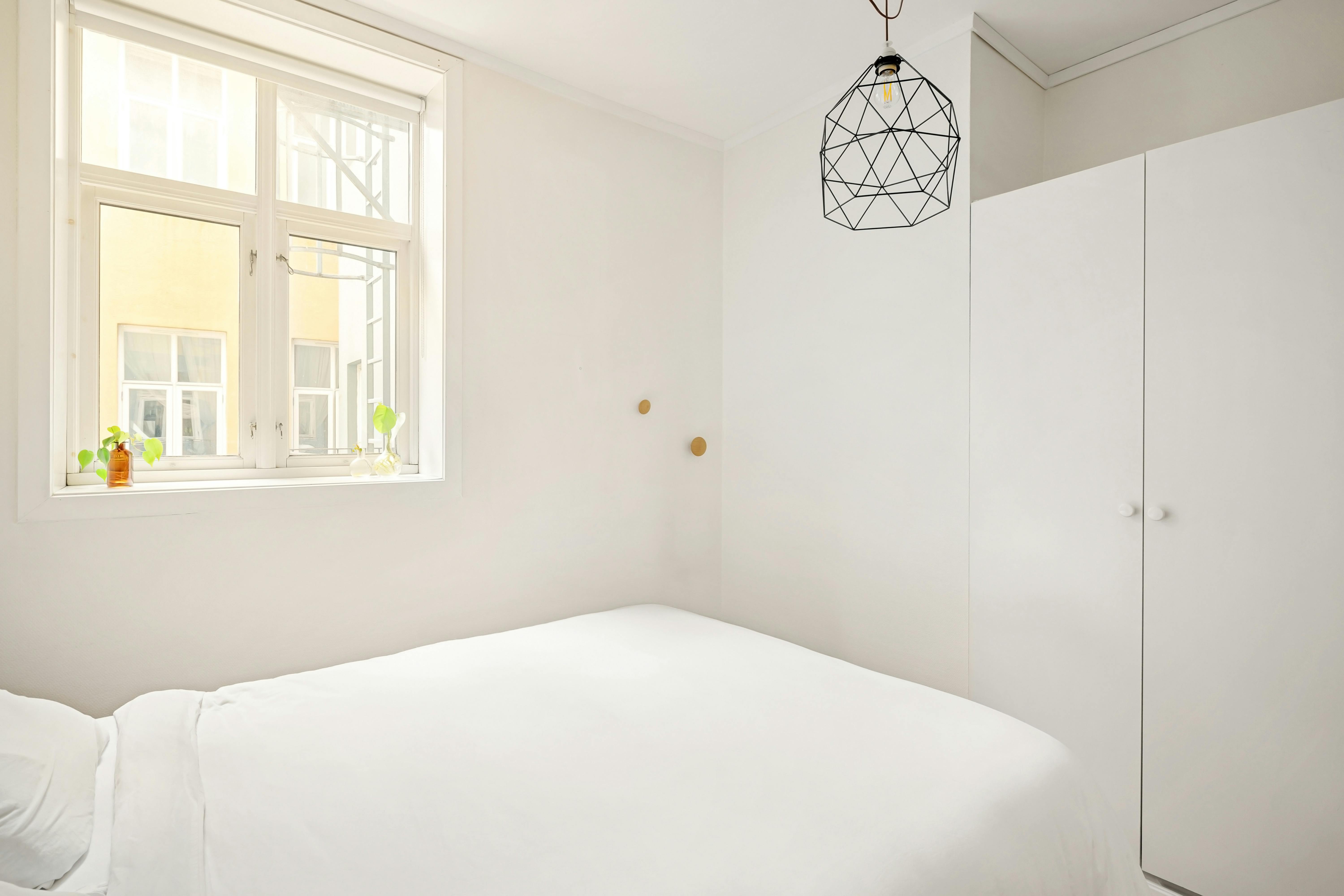 Hoher Kleiderschrank im Altbau-Schlafzimmer, sauber ausgerichtet an einer leicht unebenen Wand