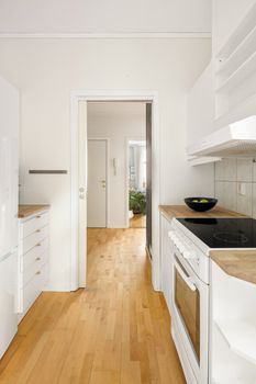 Bright and modern kitchen interior with white cabinets and wooden flooring, perfect for urban living.