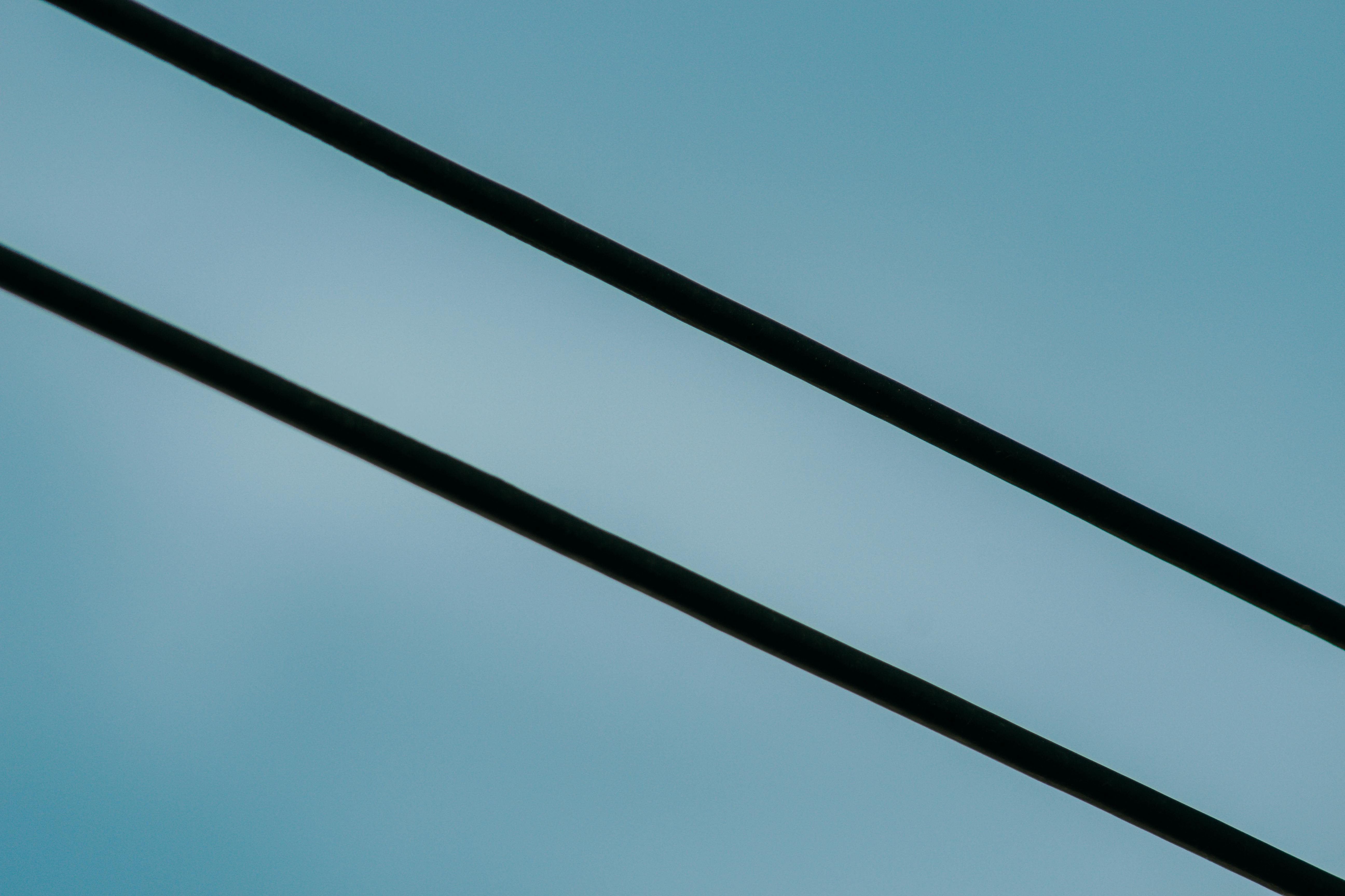 Free Minimalist photo featuring two parallel power lines against a clear blue sky, embodying simplicity and modernity. Stock Photo