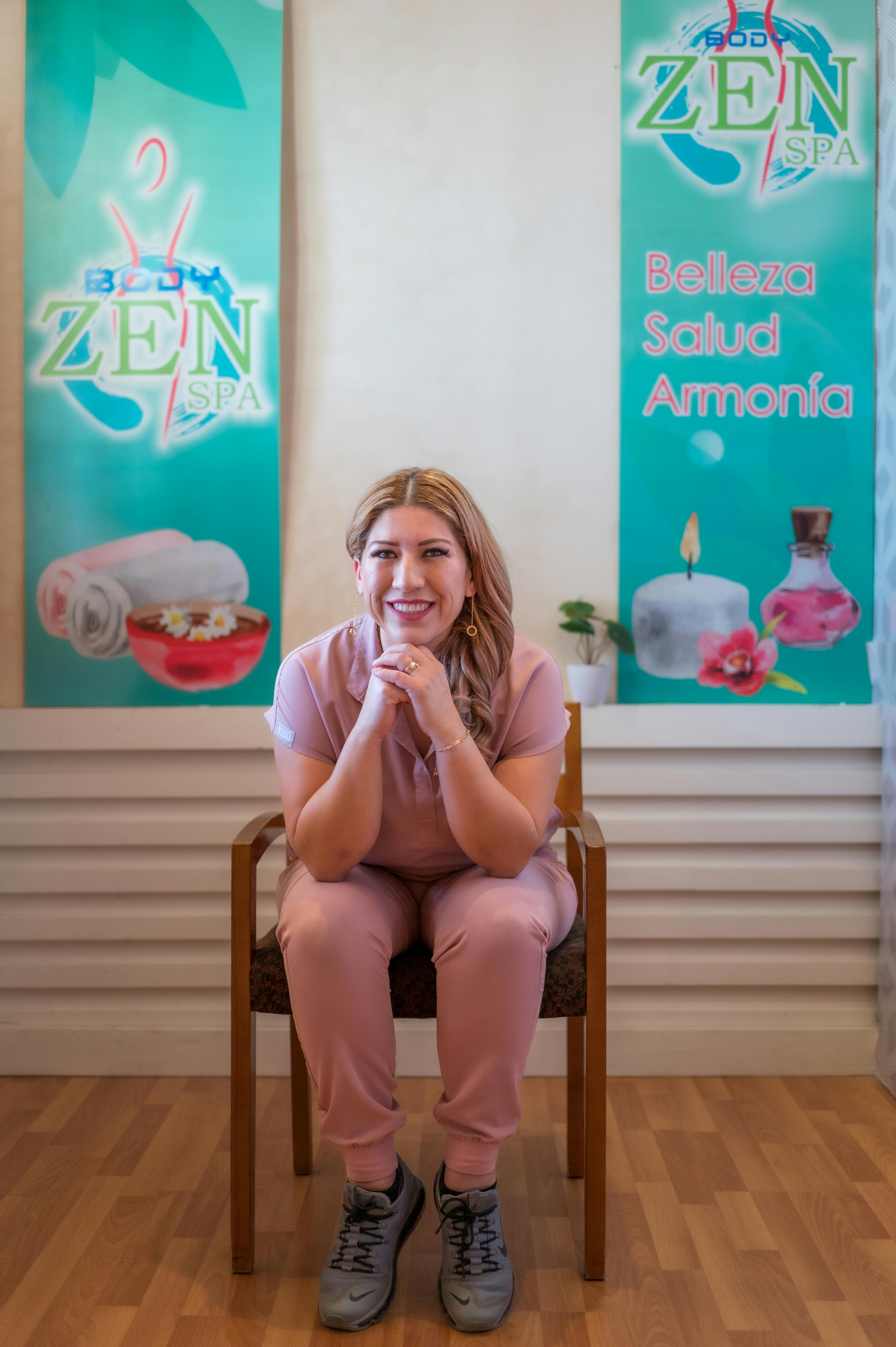 A woman sitting in a spa, smiling and promoting beauty, health, and harmony.