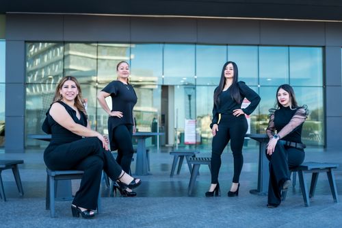 Free Four confident women dressed in black pose outside a modern building in Juárez, Mexico. Stock Photo
