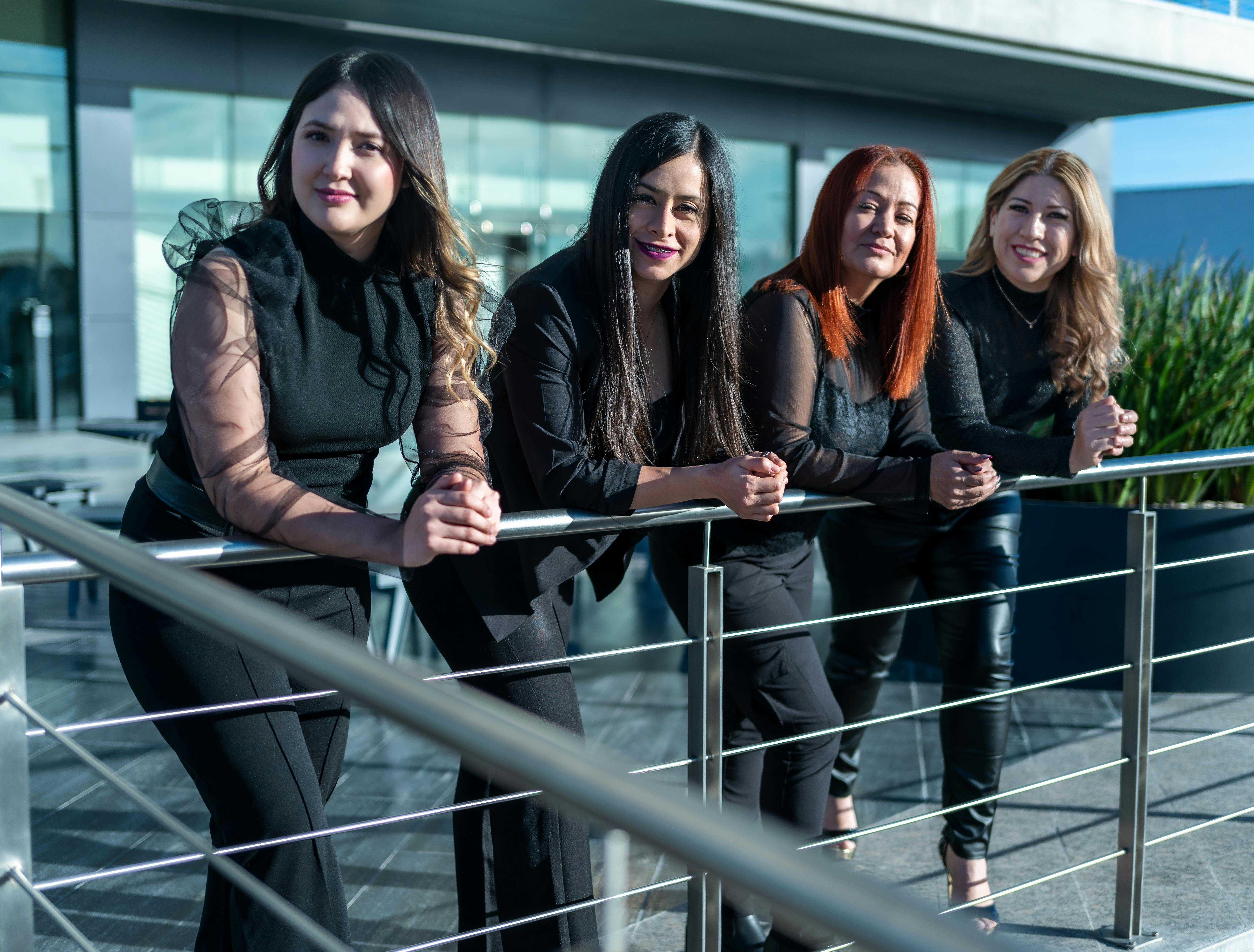 Four confident women in business attire posing outdoors, representing empowerment and leadership.