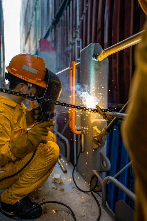 Man Wearing a Yellow Protective Clothing, Welding by a Wall