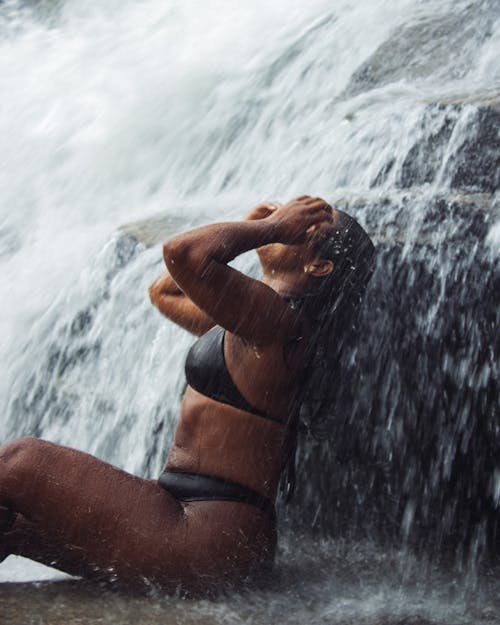 Woman Wearing a Black Bikini, Bathing under a Waterfall