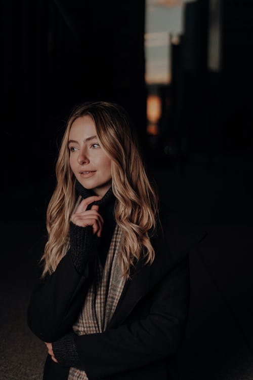 Blonde Woman in Scarf and Black Coat at Night