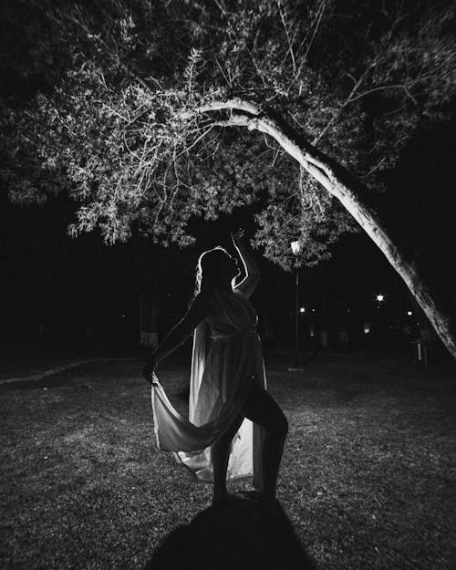 Woman in Dress Posing under Tree at Night