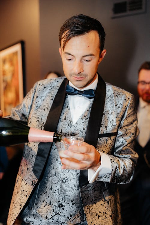 Elegant Man Pouring Champagne into a Cup at a Party 