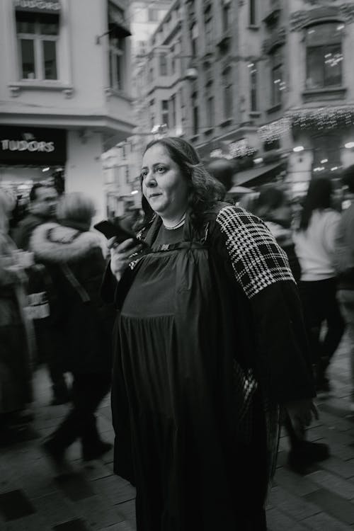 Black and White Photo of a Woman Walking on a Crowded Street 