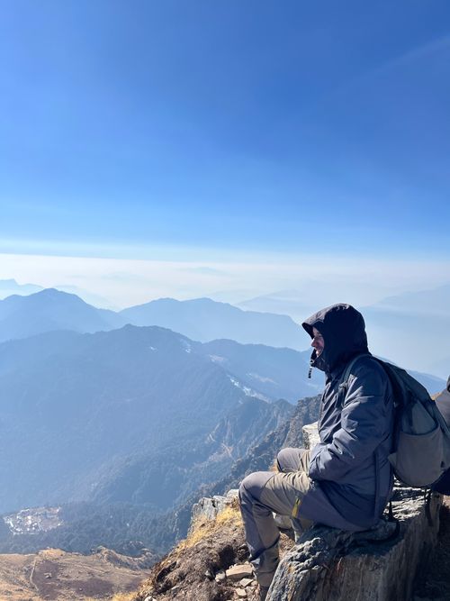 Free A solitary hiker sits atop a mountain peak, embracing breathtaking views of layered ranges. Stock Photo