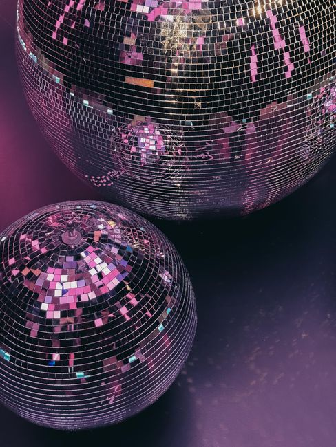 Close-up of shiny disco balls reflecting purple light for party decor.