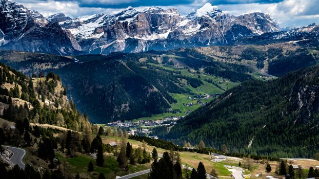 A breathtaking aerial view of the Dolomites with lush valleys and snowy peaks.