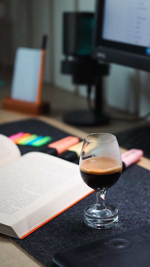 Black Coffee in Glass by Book on Desk