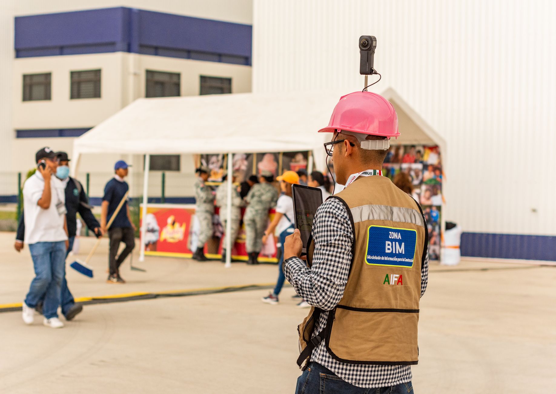 A construction worker with a tablet and camera inspects a site, using modern technology for documentation.