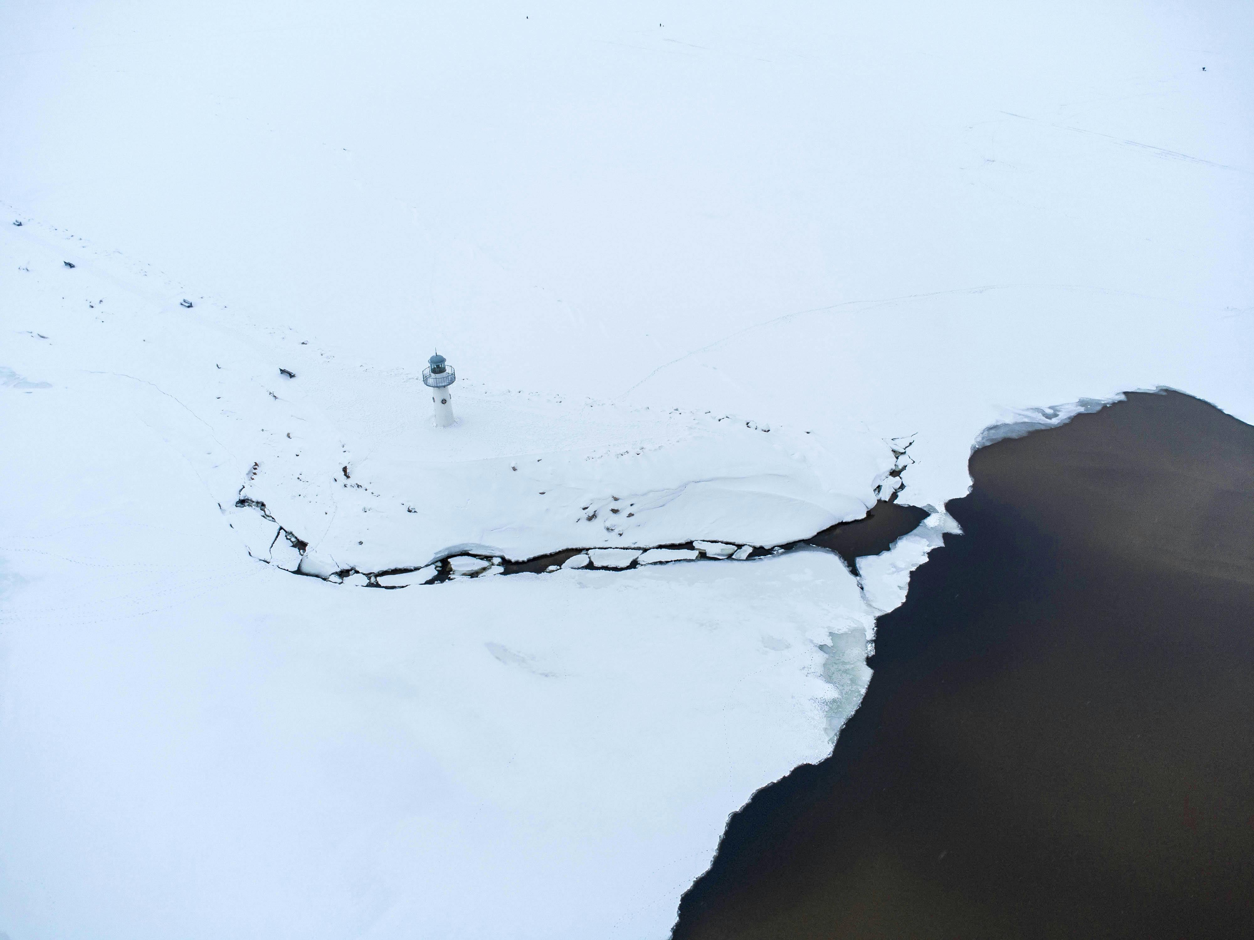 Aerial view of a snow-covered landscape with a lighthouse beside a frozen bay, Tolyatti, Russia.