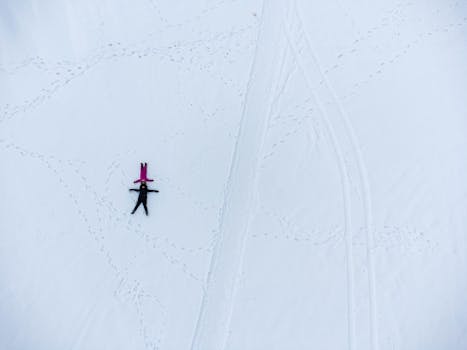 Aerial shot of two people making snow angels on a snowy field in Tolyatti, Russia.