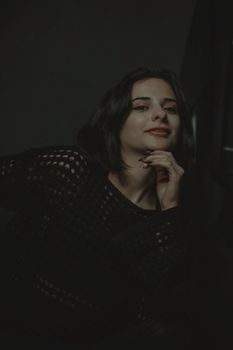 Moody portrait of a woman in a dark knit sweater with confident expression.