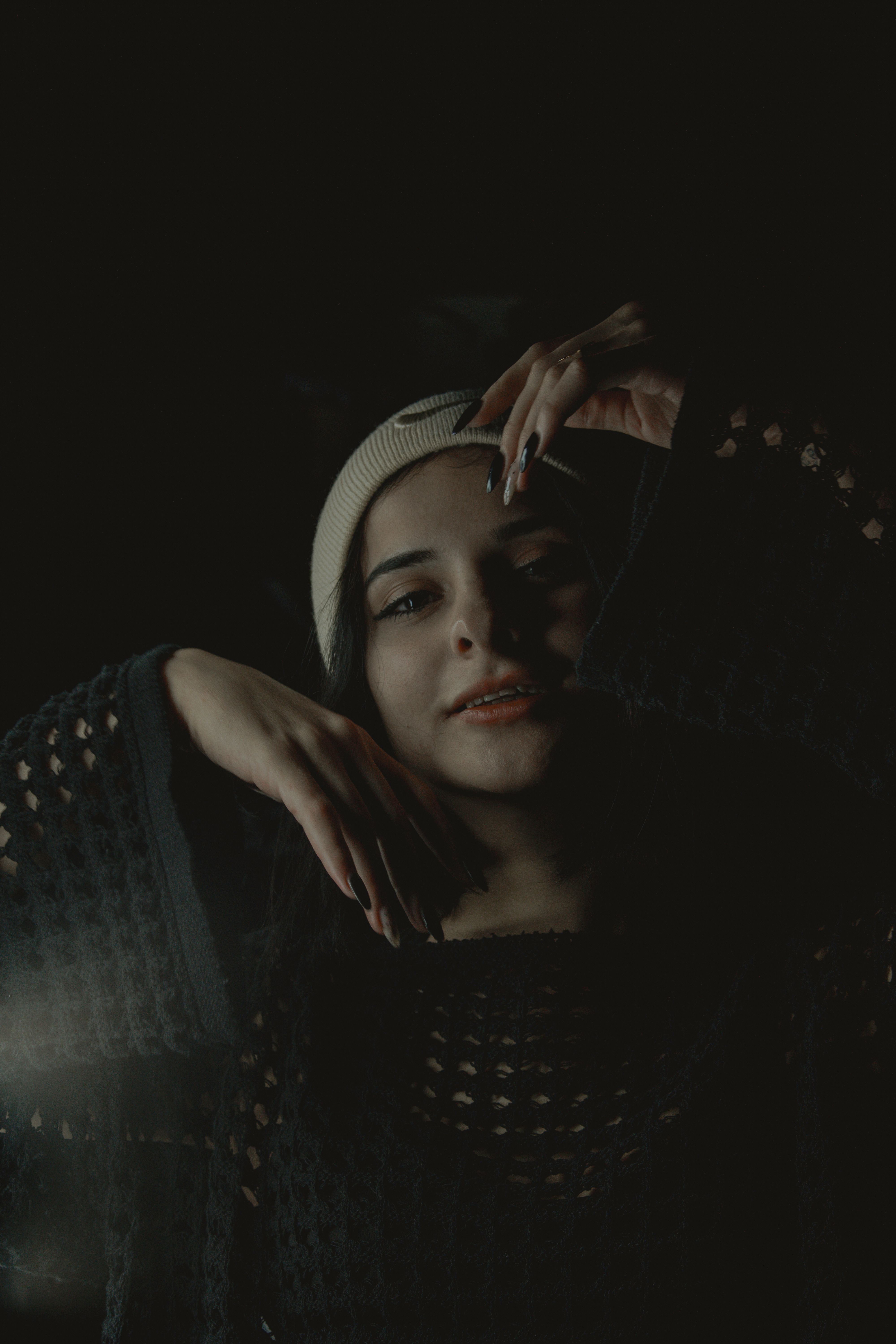 Artistic portrait of a young woman wearing a beanie and open stitch sweater, exuding joy.