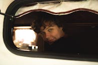 一个年轻人热情地微笑着，在舒适的露营车里，捕捉到了放松和旅行的时刻