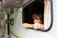 夏日里，一名化了妆的年轻女子在露营车里凝视着外面，放松身心