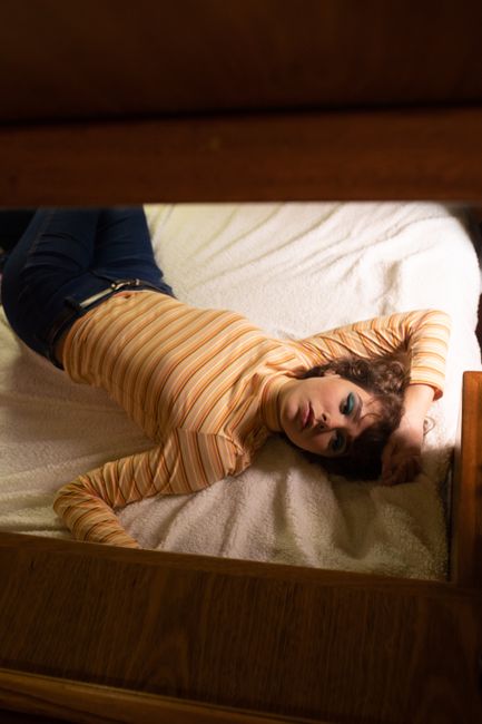A woman in a striped top relaxes on a bed, capturing a moment of comfort and tranquility.