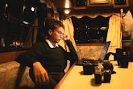 一个人在温暖的灯光下，用笔记本电脑在舒适的房间里工作，周围布满了摄像头