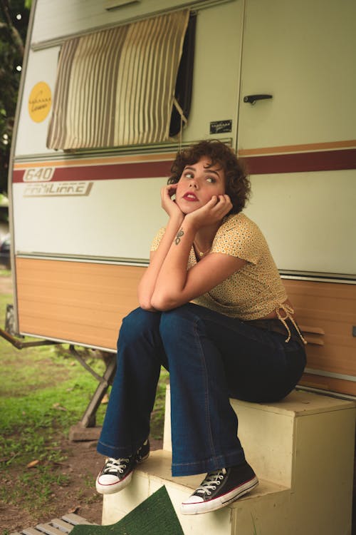 Woman Sitting on Stairs Near Travel Trailer