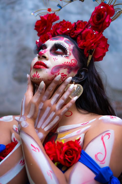 Free A beautiful woman adorned in traditional Day of the Dead makeup and red roses, captured in vivid detail. Stock Photo