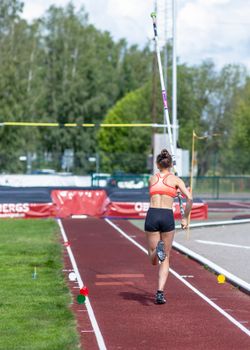 Female athlete in sportswear preparing for pole vault outdoors on a sunny day. — photo by Maria Argiroudaki