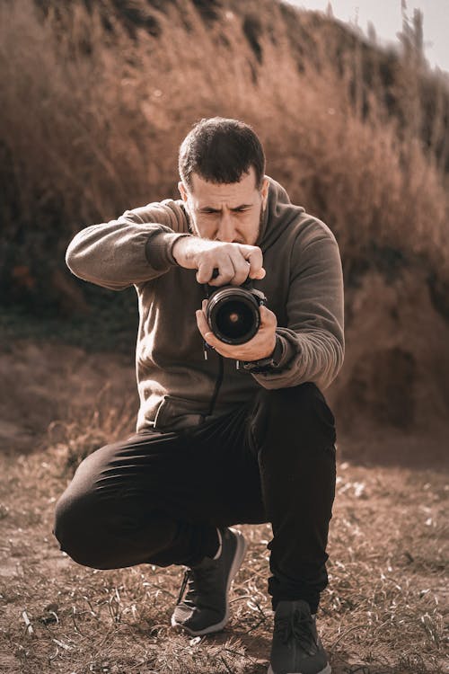 Man Crouching with Camera and Taking Pictures
