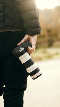A photographer holds a DSLR camera with a telephoto lens outdoors in Collo, Algeria.