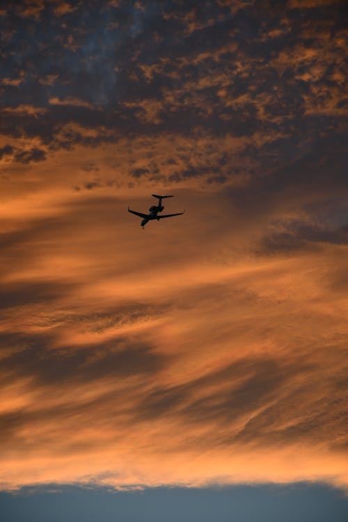 Airplane in Red Cloudy Sky at Sunset