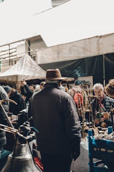 A bustling indoor flea market scene with various vendors and shoppers browsing stalls.