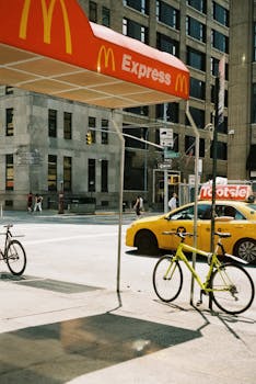 New York City street scene featuring McDonald's awning, yellow cab, and bicycles.