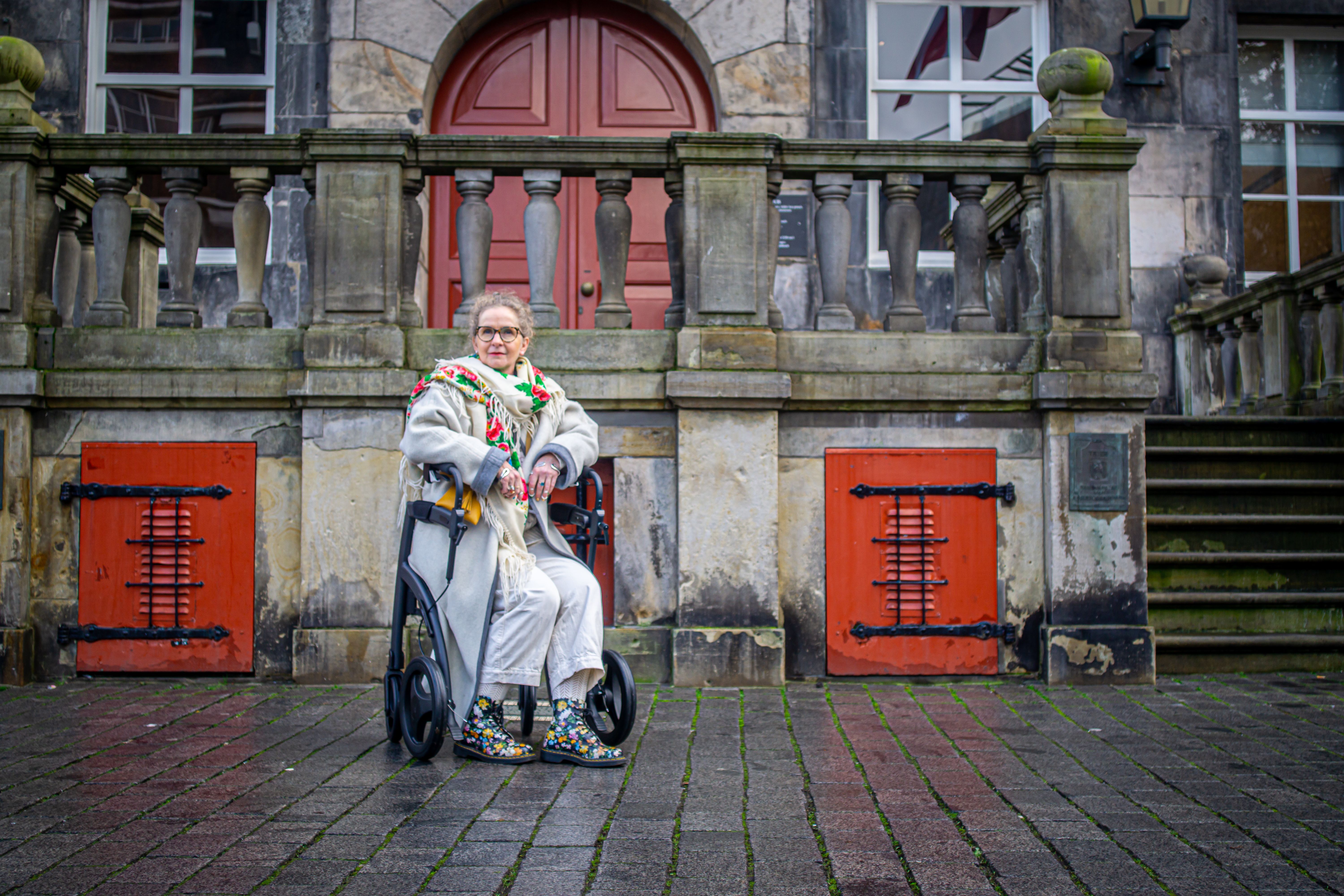 Elegant senior woman sitting outdoors with a walker, embracing urban fashion.