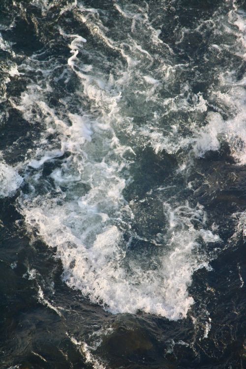 Free A top-view of churning ocean waves with white foam on the surface. Stock Photo
