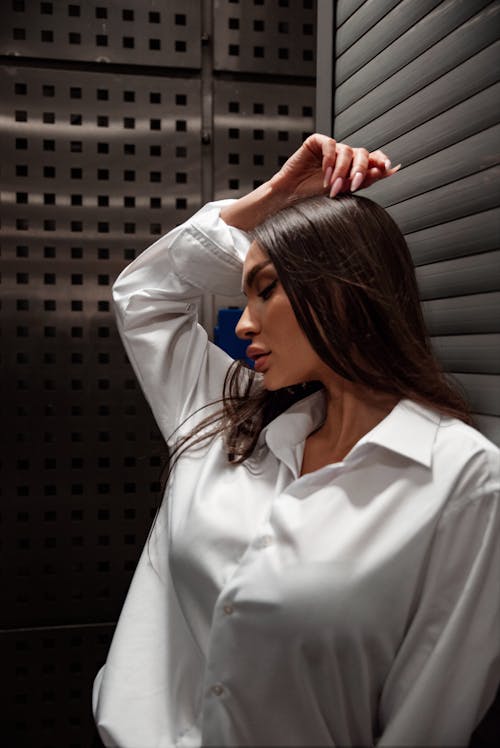 A woman in a white shirt leaning against a wall