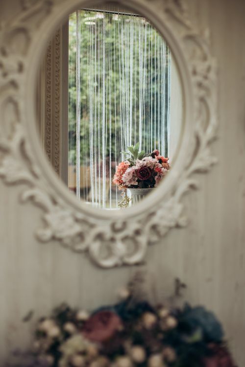 Free Refined flowers elegantly reflected in an ornate vintage mirror with soft lighting. Stock Photo
