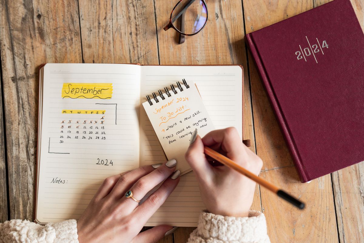Pessoa escrevendo uma lista curta em um caderno, representando preparo leve para a semana
