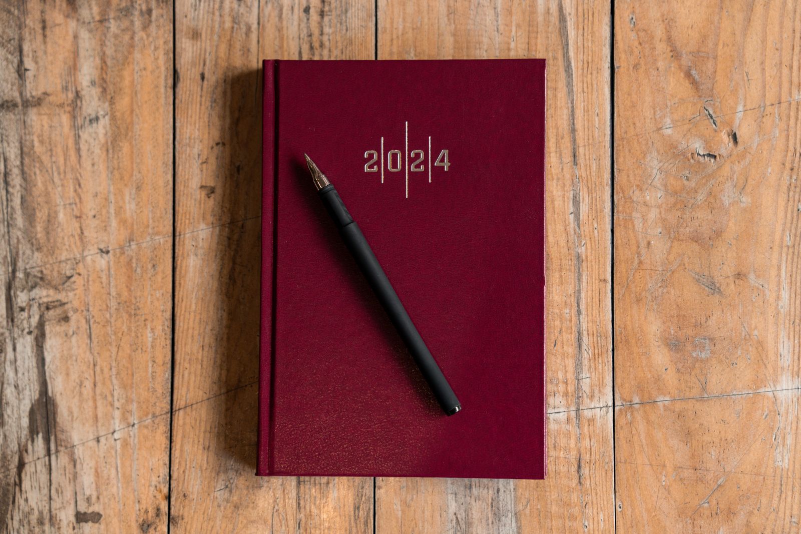 Red planner and pen on a wooden desk